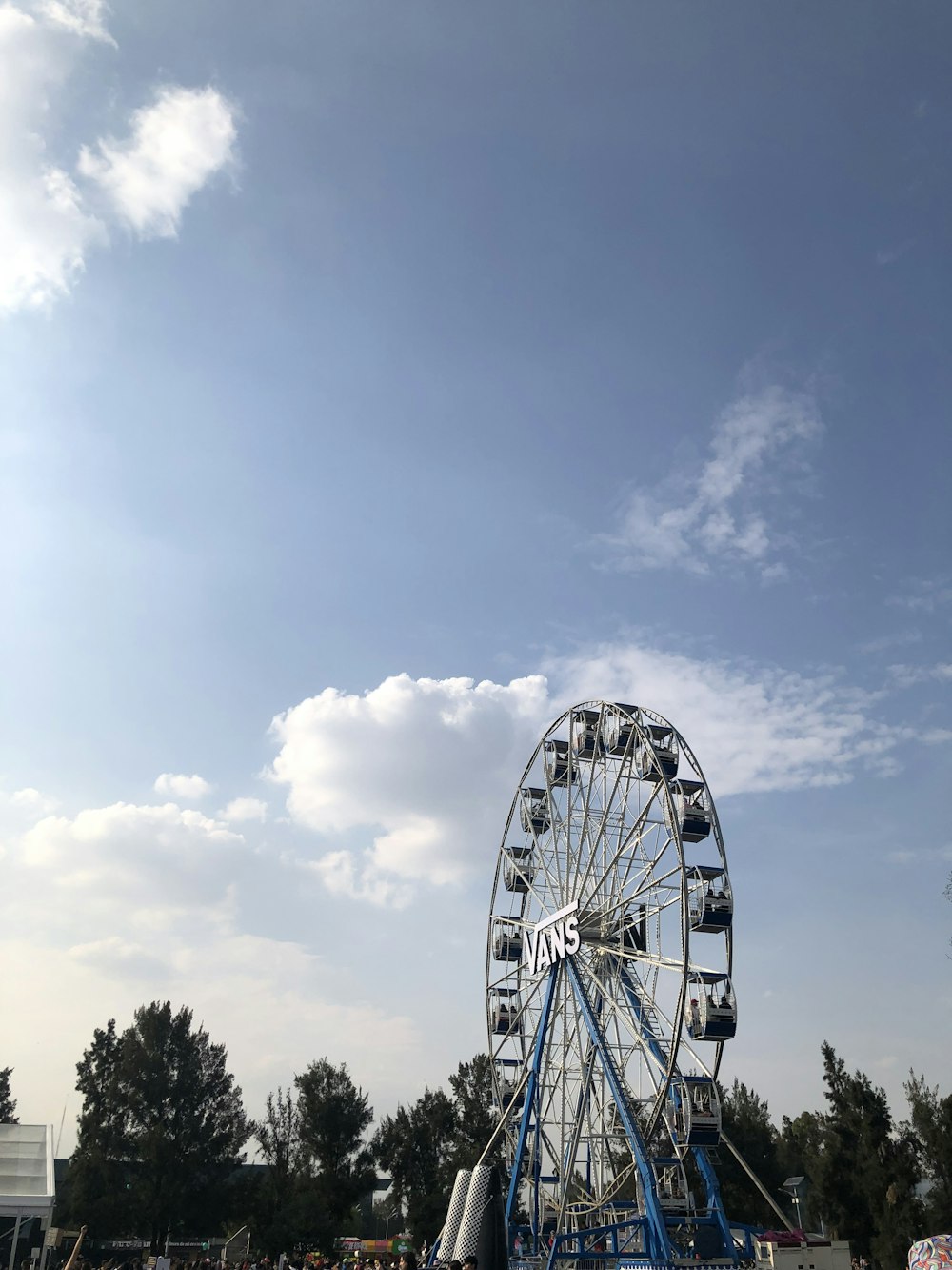 a ferris wheel with trees and blue sky