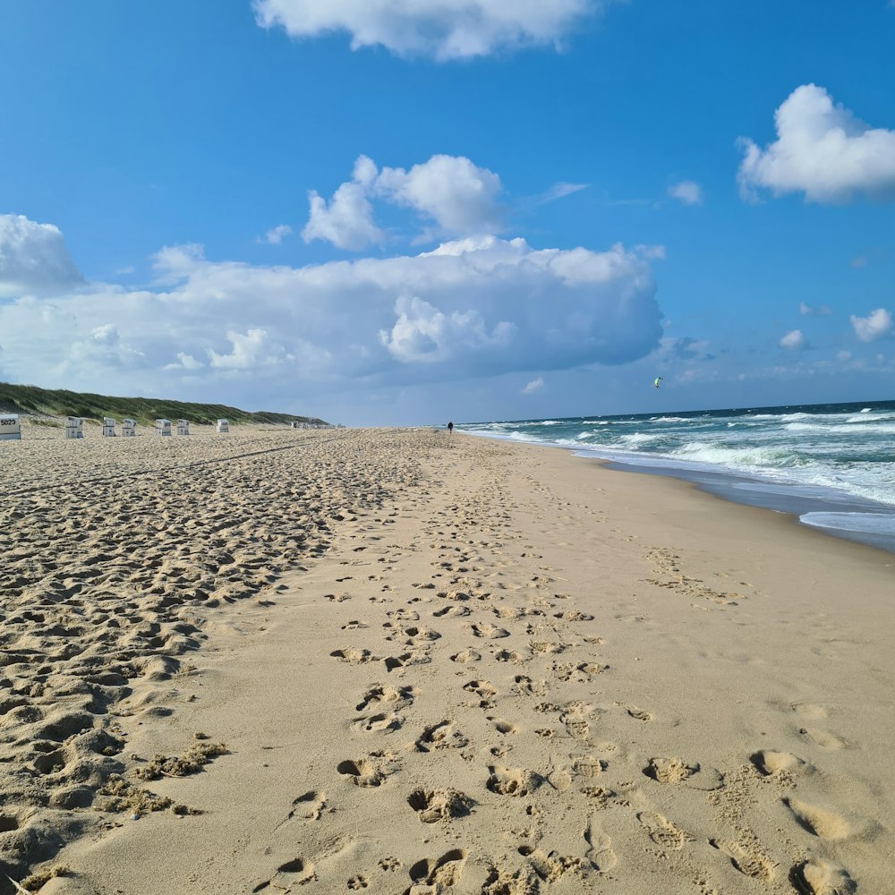 a sandy beach with waves and blue sky