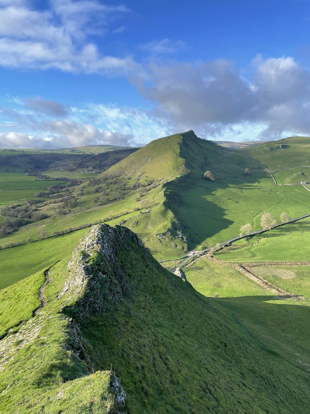a grassy hill with a road with Quiraing in the background