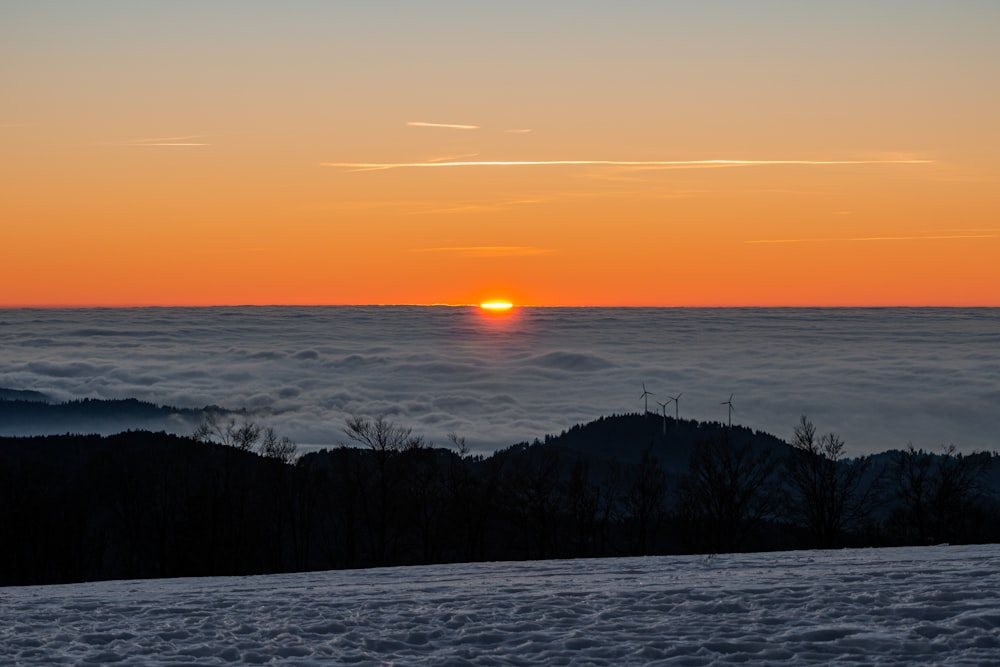 um pôr do sol sobre uma paisagem nevada