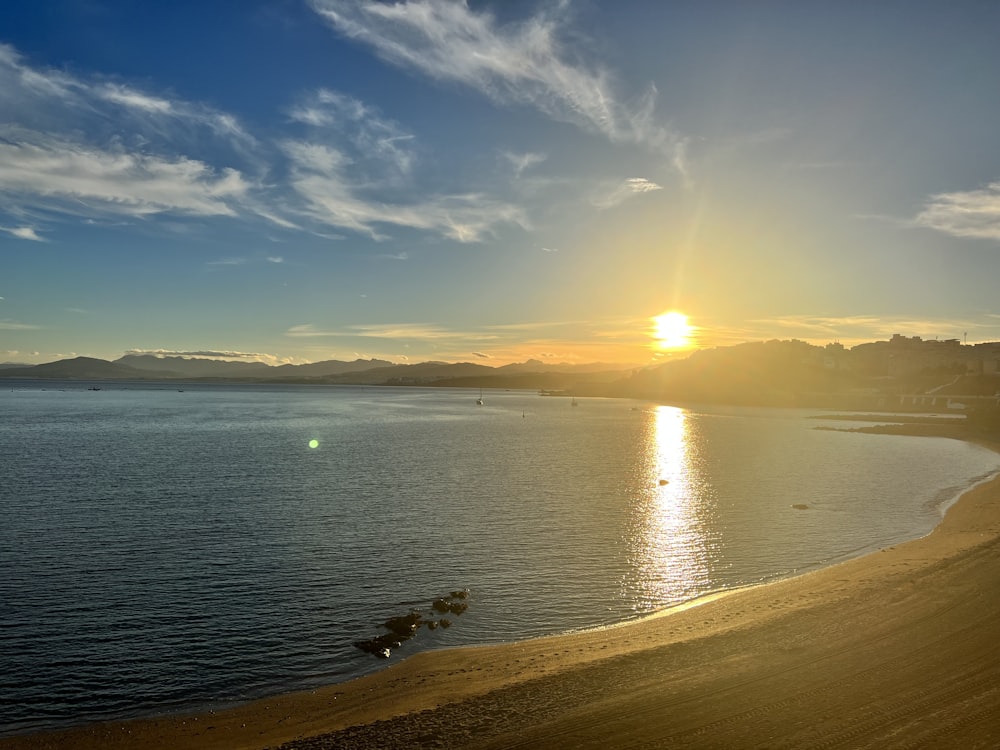 a beach with a body of water and a sunset