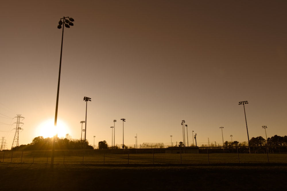 a field with a row of street lights and a sunset