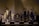 A stylized image of a chessboard with vertically elongated, abstract chess pieces. The pieces have an artistic, distorted appearance with a mix of dark and light tones that create a surreal atmosphere. The background is muted, focusing attention on the chessboard and its unique pieces.