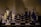 A stylized image of a chessboard with vertically elongated, abstract chess pieces. The pieces have an artistic, distorted appearance with a mix of dark and light tones that create a surreal atmosphere. The background is muted, focusing attention on the chessboard and its unique pieces.