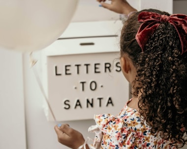 Child's name written on a holiday scroll with elves dancing around.