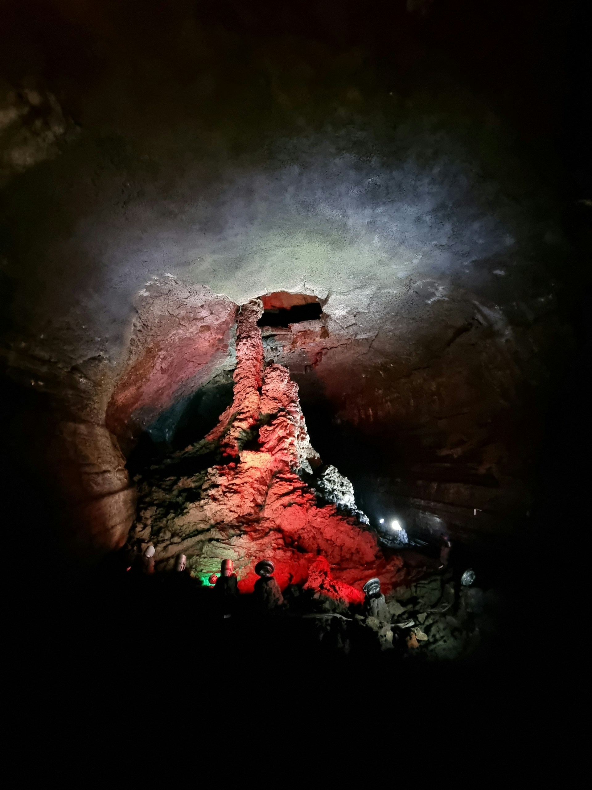 Adventurers exploring a deep cave with dramatic lighting highlighting the rocky formations inside.