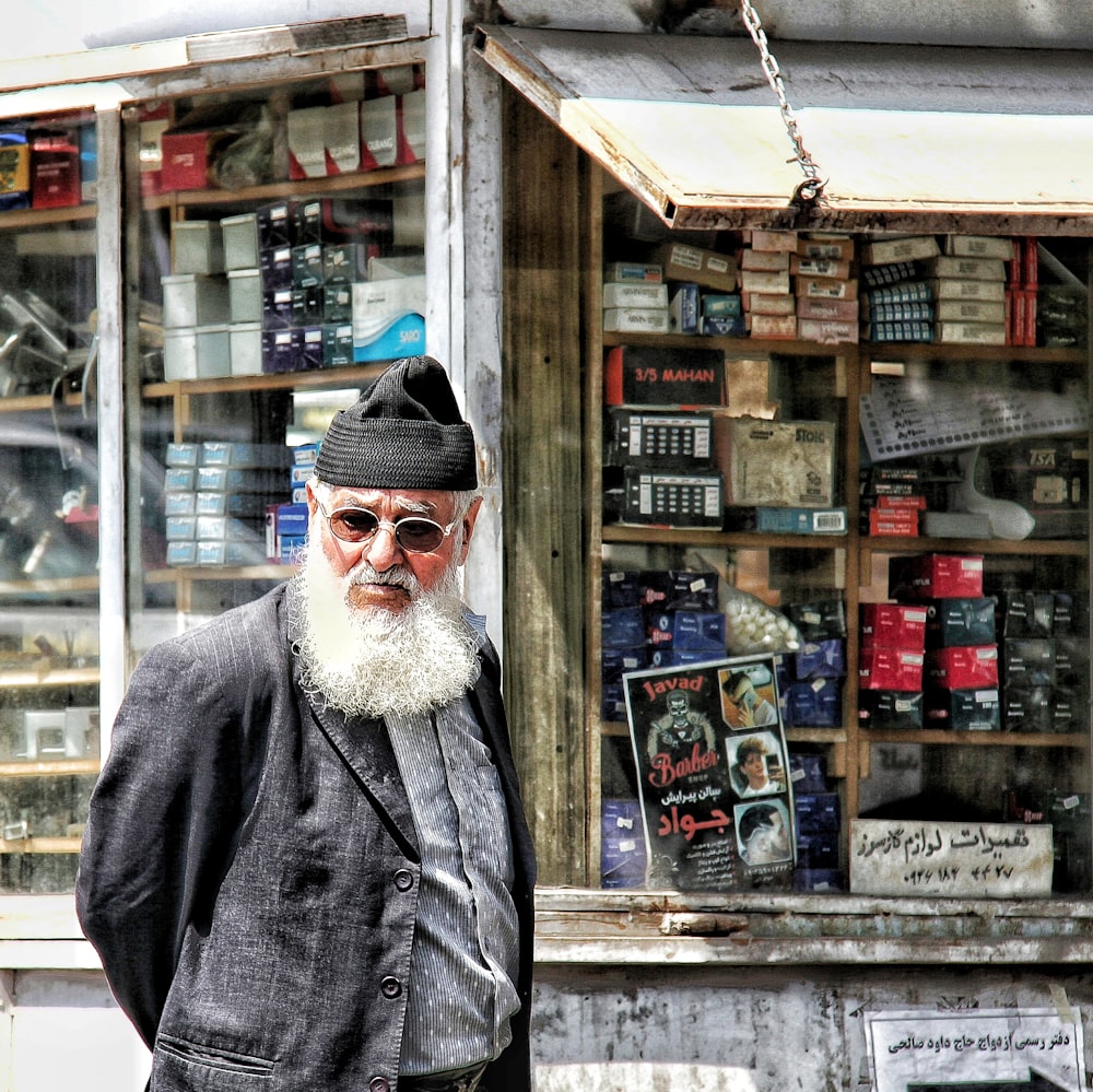 a person with a beard and hat standing in front of a store