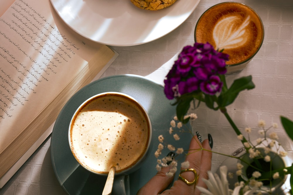 a cup of coffee and a plate of flowers on a table