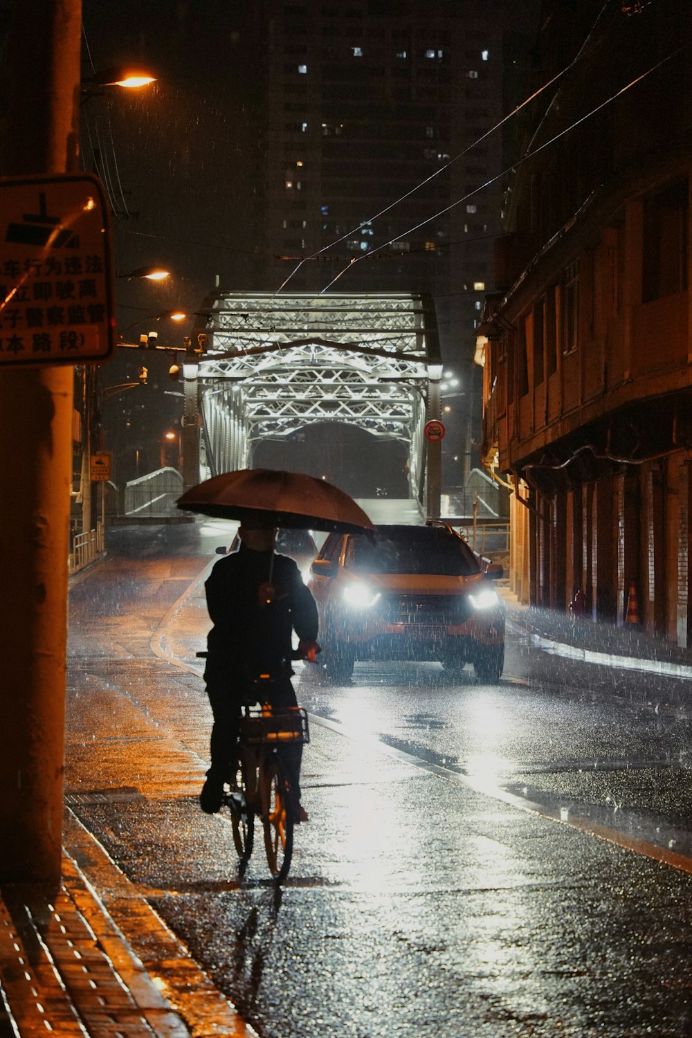 a person riding a bicycle with an umbrella on a rainy night