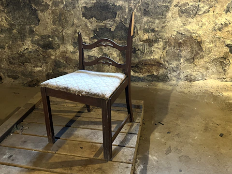 Photo of an old, scratched wooden chair with faded paint in a rustic workshop setting.
