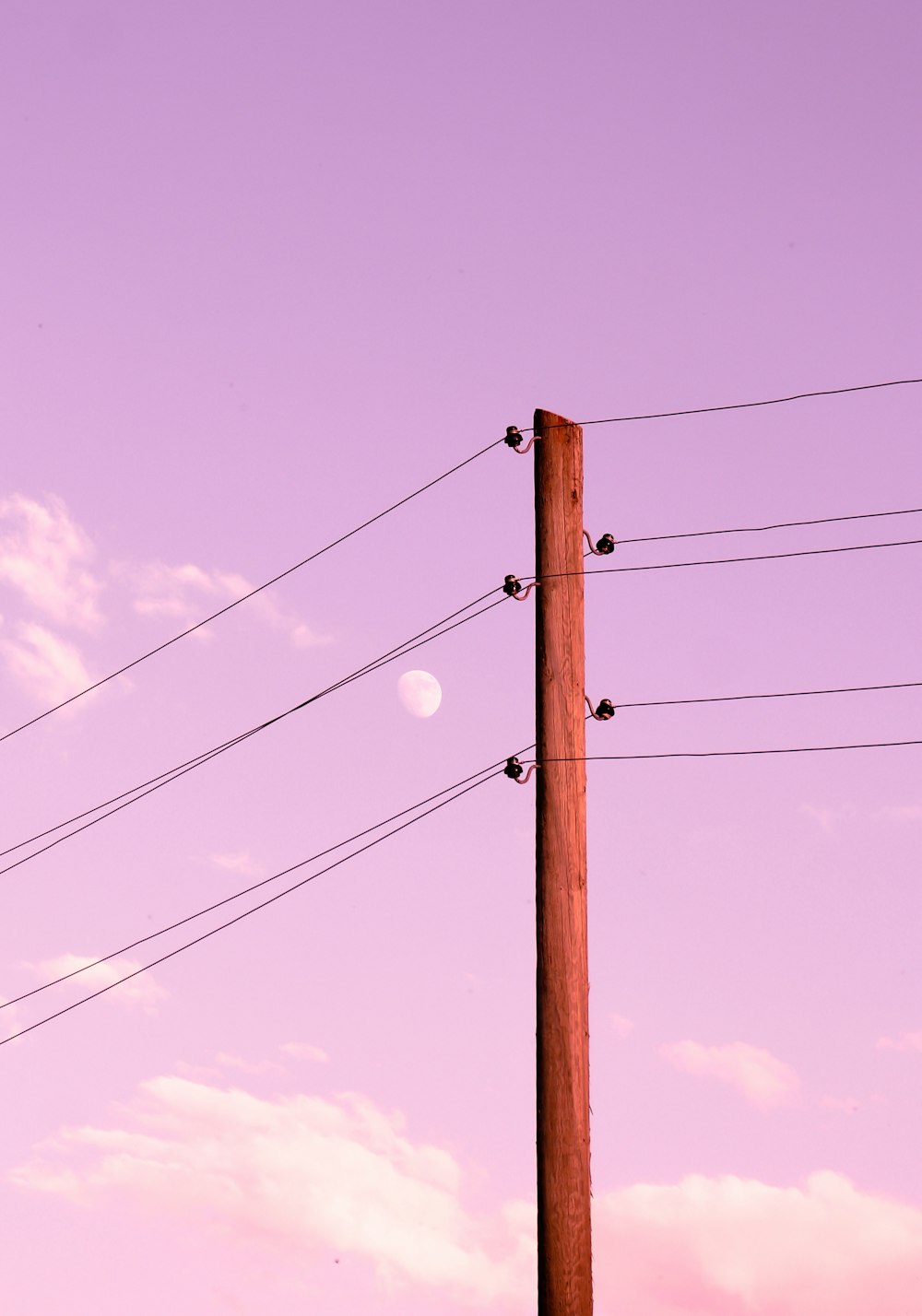 a pole with wires and a moon in the background
