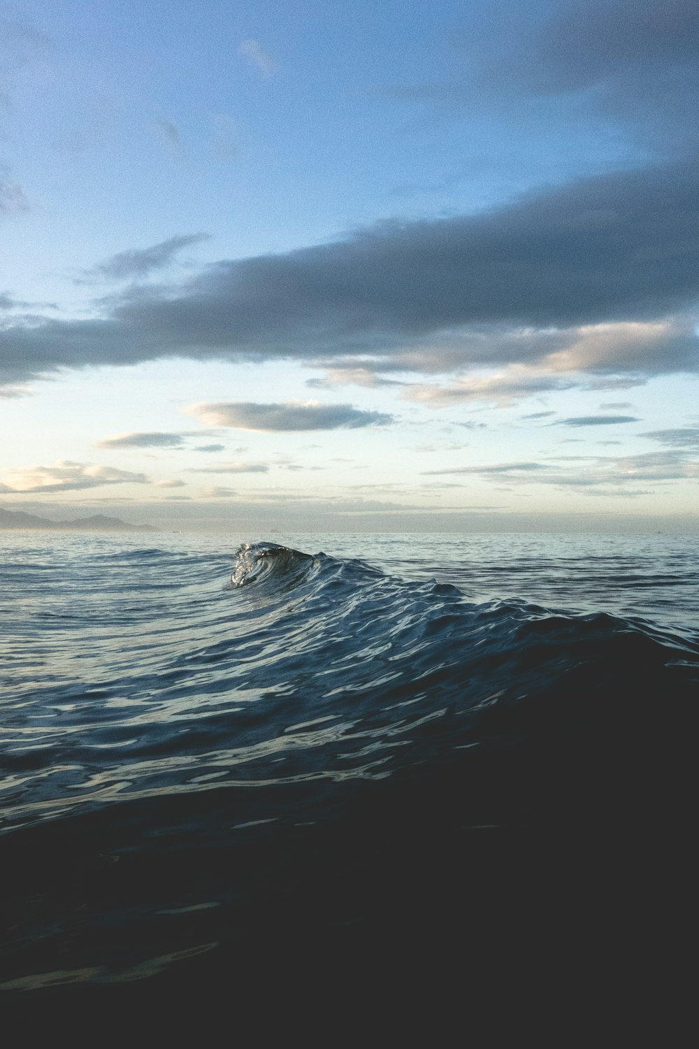 a body of water with waves and a rock in the middle