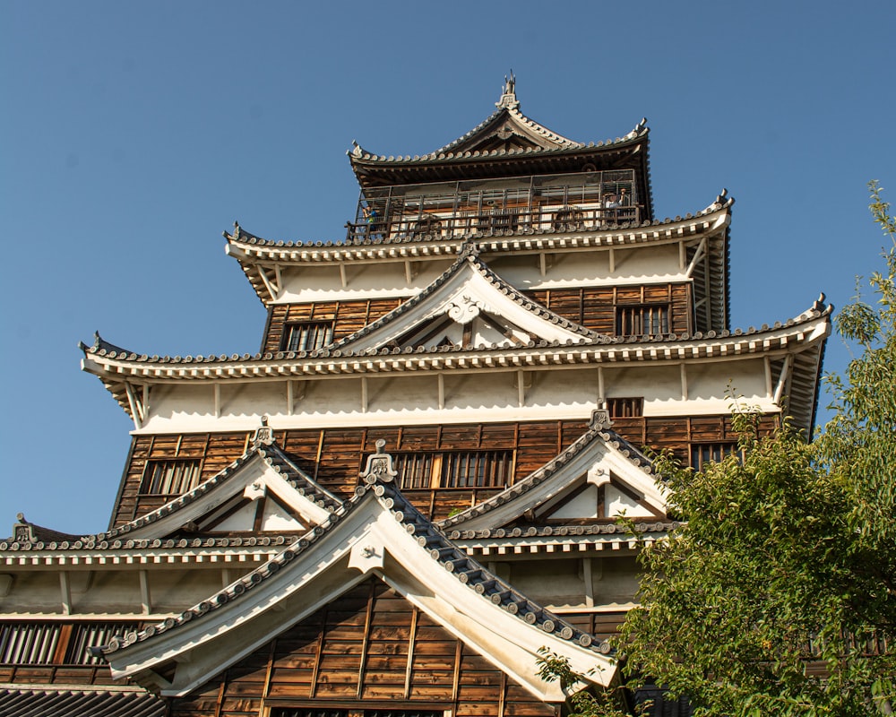 um grande edifício de estilo asiático com o Castelo de Hiroshima ao fundo