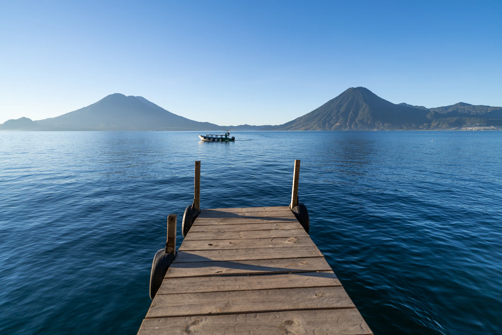 Lake Atitlan with volcanoes and a wooden dock