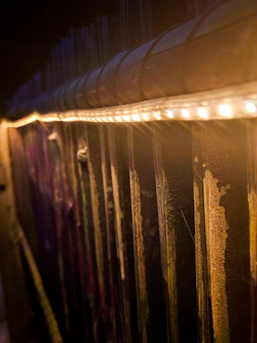 Warmly lit private golf suite with dark shiplap walls, wooden framing, and black turf.