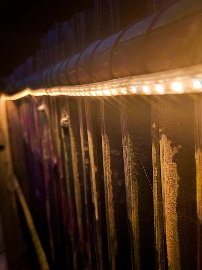 Warmly lit private golf suite with dark shiplap walls, wooden framing, and black turf.