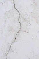 Before and after images of a wall with cracks repaired and freshly painted in a warm tone.