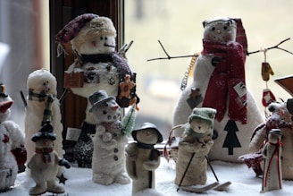 A collection of colorful winter knit hats and scarves arranged on a snowy windowsill.