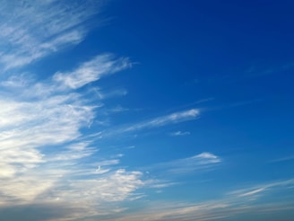 Sky blue horizon with wispy clouds above a brown earth landscape.