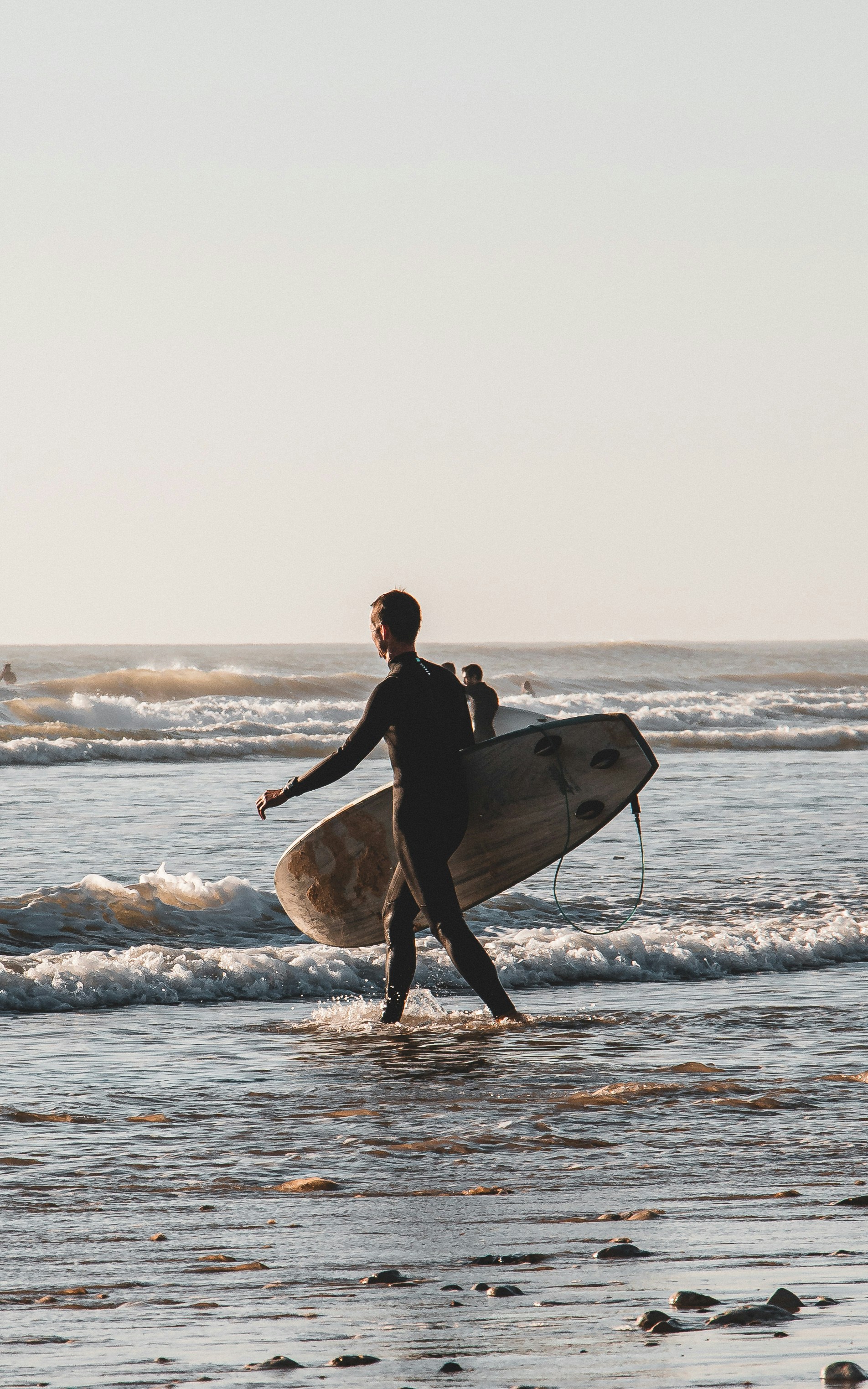 Un uomo che trasporta una tavola da surf sulla spiaggia