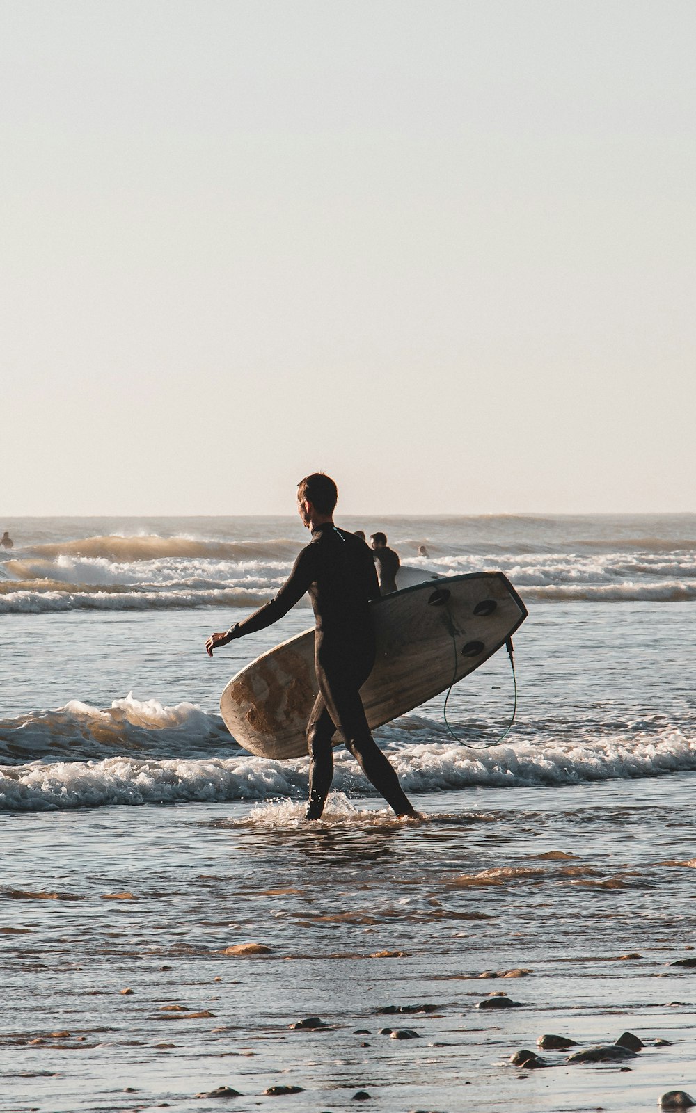 a man carrying a surfboard on the beach