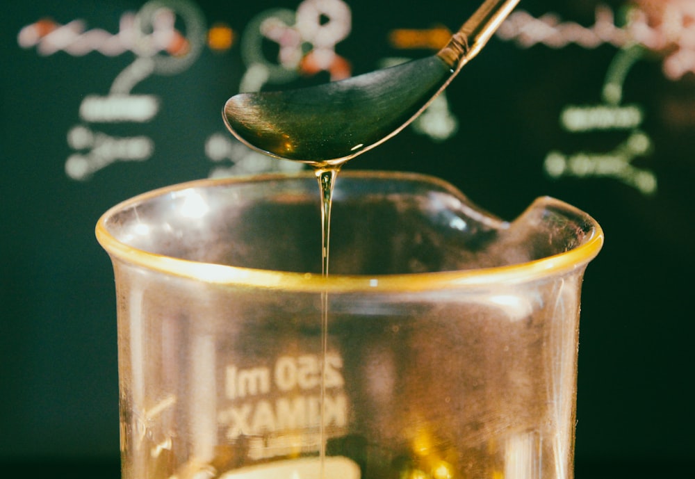 a glass of liquid with a green leaf on top