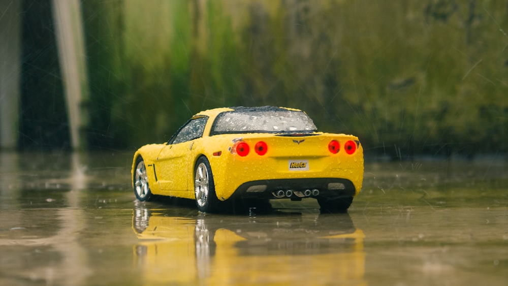a yellow sports car on a wet road