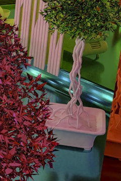 A visually striking scene featuring abstract plants with vibrant geometric foliage and twisted trunks in decorative pots. The composition includes multiple colors and textures that blend into a modern, artistic setting.