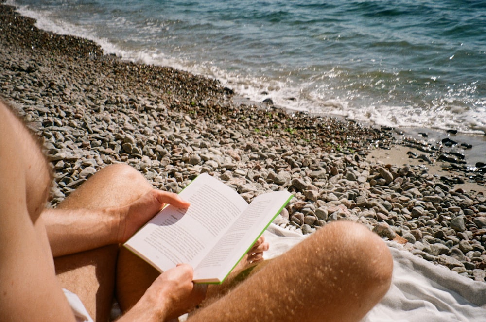 a person reading a book on a beach