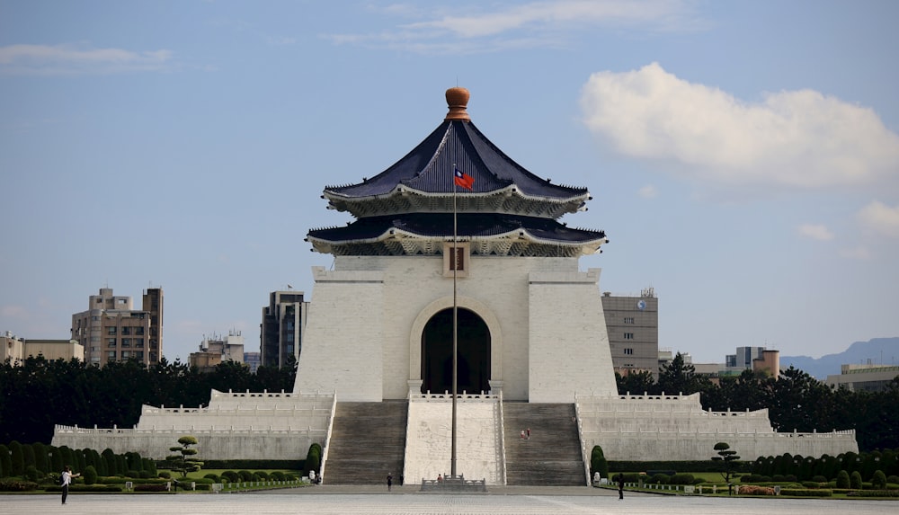 un grand bâtiment blanc avec un toit bleu et un toit noir et rouge avec le mémorial de Chiang Kai-shek en arrière-plan