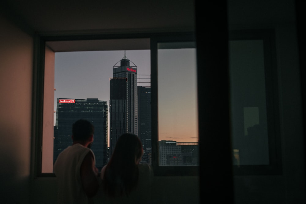 a man and woman looking out a window at a city