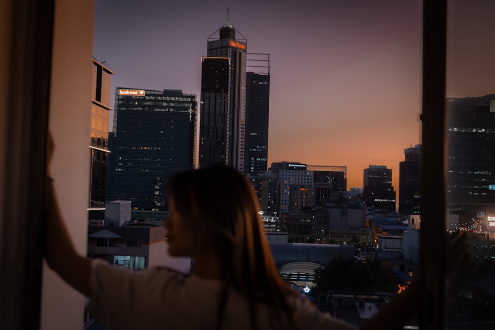 a person looking out a window at a city