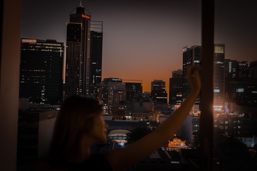 a person looking out a window at a city at night