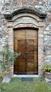 Rustic style metal door with decorative wrought iron details, set against a brick wall.