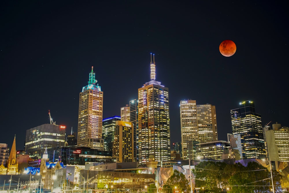 a city with tall buildings and a moon in the sky