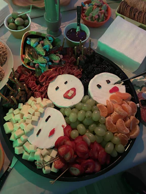 A colorful plate of kid-friendly snacks arranged like a smiling face on a wooden table.