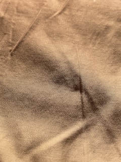 Close-up of textured fabric in warm brown shades folded neatly on a wooden table.