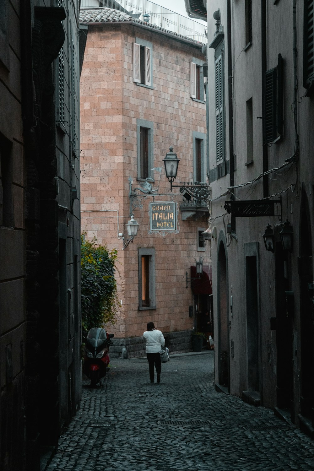 a person walking down a cobblestone street between buildings