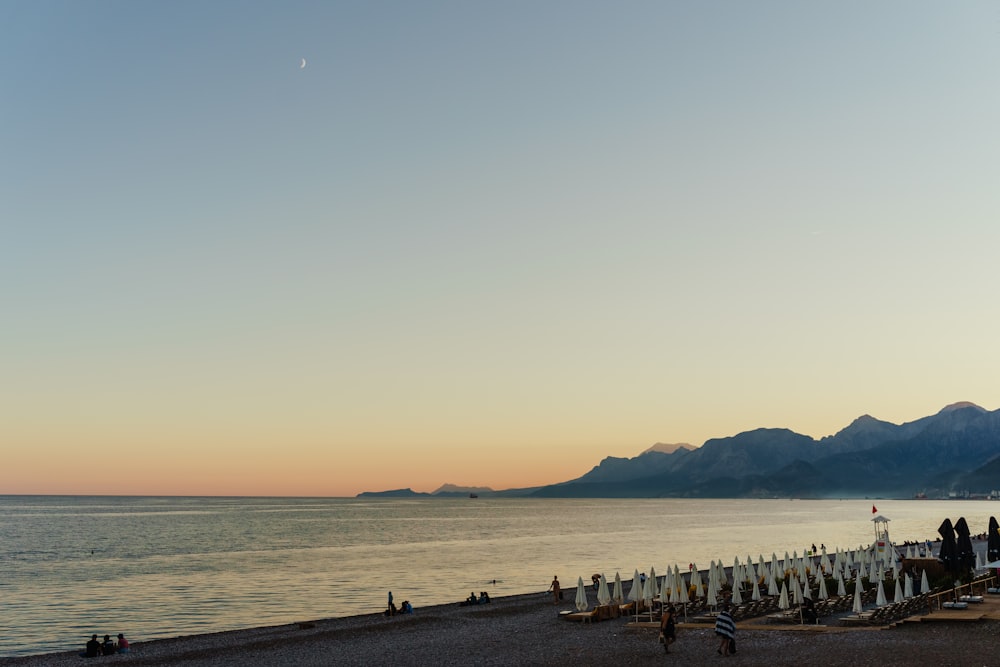 Una playa con gente y un cuerpo de agua al fondo