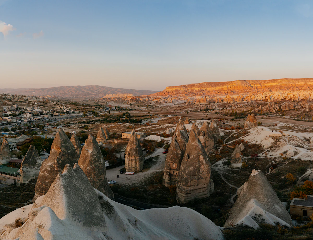Fairy chimneys above Göreme in evening light, with the town and a long flat-topped ridge behind