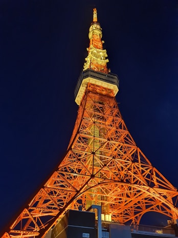 Nighttime scene showing the elegant structure of the solar tower with its battery and light mast clearly visible.