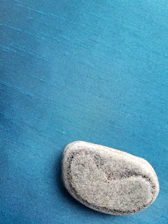 Close-up of a smooth, polished holy stone resting gently on soft beige fabric.