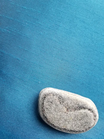 Close-up of a smooth, polished holy stone resting gently on soft beige fabric.