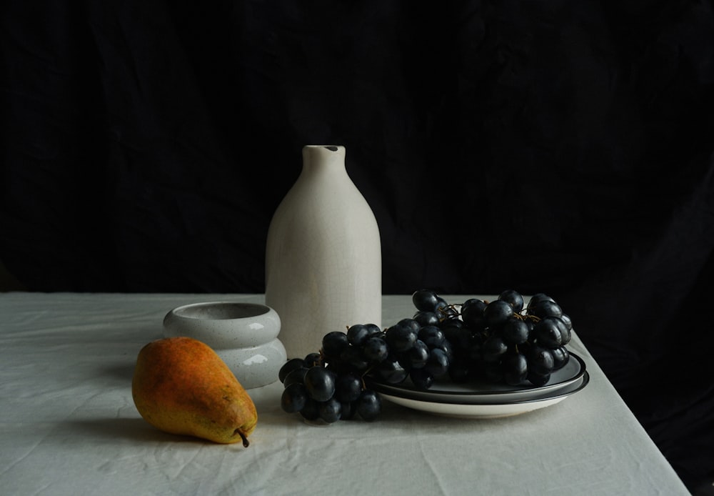 a vase and grapes on a table