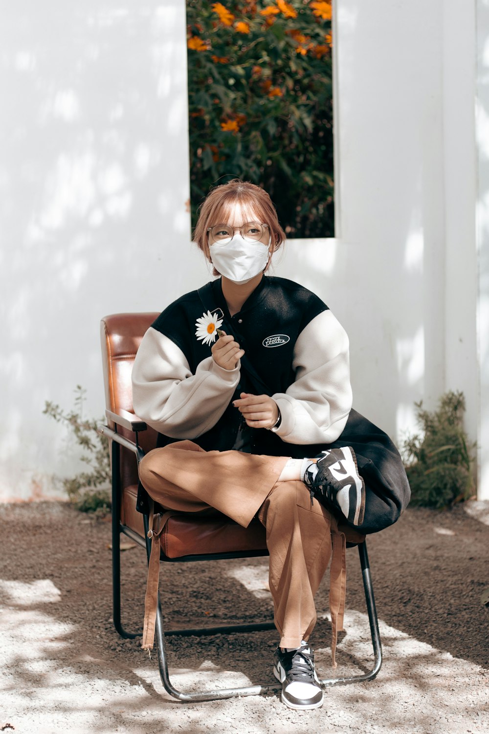 a man with a face mask sitting in a chair outside