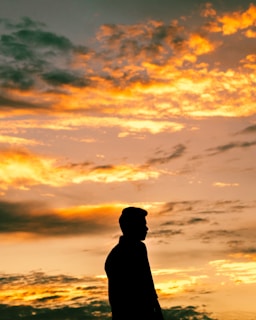 A striking outdoor portrait of an individual with a dramatic sunset backdrop.