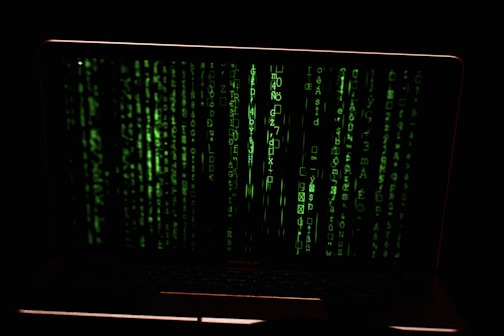 Green digital code streams vertically across the screen, resembling a hacker or cyber interface against a dark background.