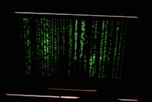 Green digital code streams vertically across the screen, resembling a hacker or cyber interface against a dark background.