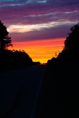 A vibrant sunset casting shadows on a deserted road.