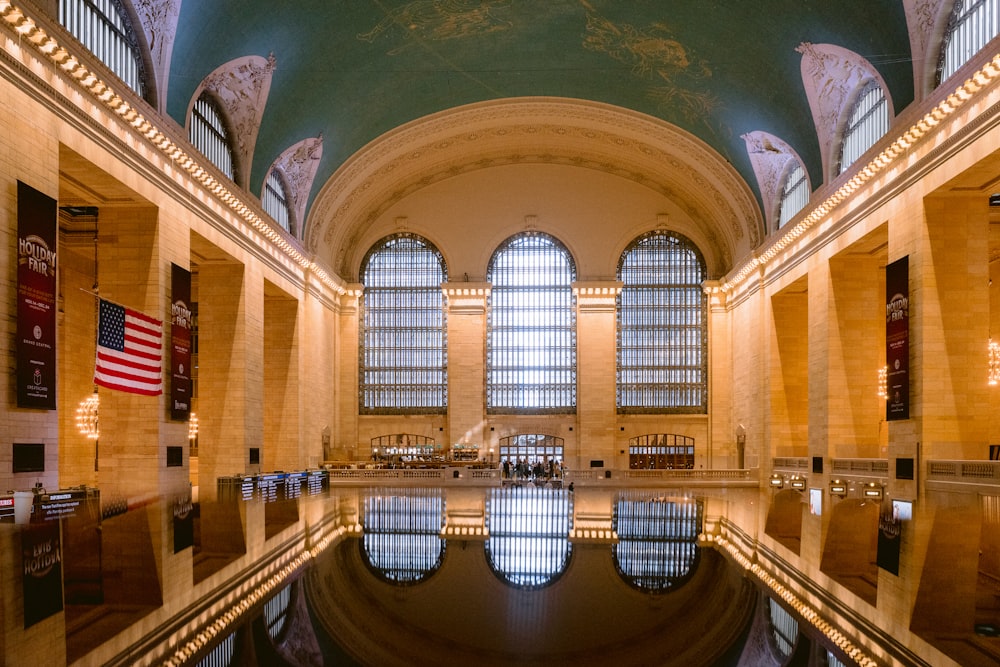 una gran sala con piscina y banderas con Grand Central Terminal al fondo